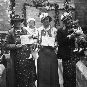 women holding babies and signs