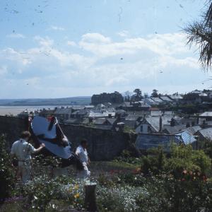 Old Oss being led through a garden, with the sea and rooftops in background
