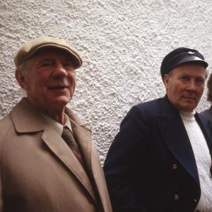 Two men and a woman stood against a wall