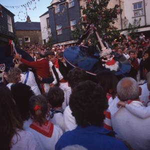 Blue Ribbon oss and Obby Oss dancing together under the Maypole in evening