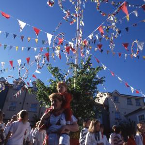 Girl on woman's shoulders under maypole