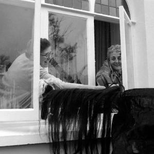 Old Oss being stroked by women from inside house