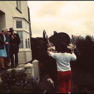Old Oss dancing in someone's garden and Master of Ceremonies greeting women at their front door
