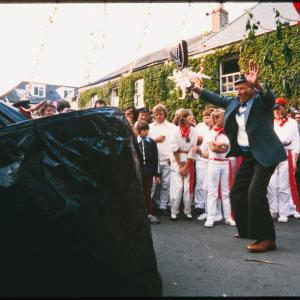 Man teasing Old Oss under maypole at sunset