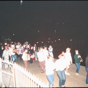 People in costume playing instruments walking along road at night
