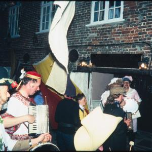 People in costume playing instruments walking along road at night