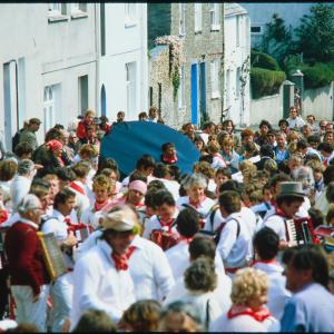 Old Oss rider amongst procession in road, without hat on