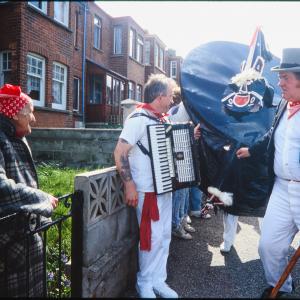 Old Oss Master of Ceremonies greeting woman at her garden gate