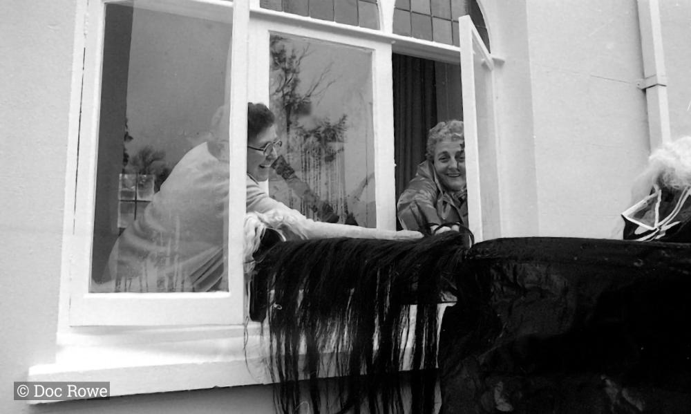 Old Oss being stroked by women from inside house