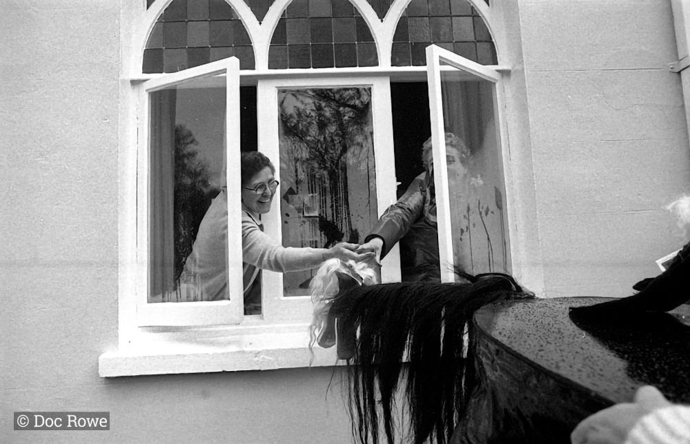 Old Oss being stroked by women from inside house