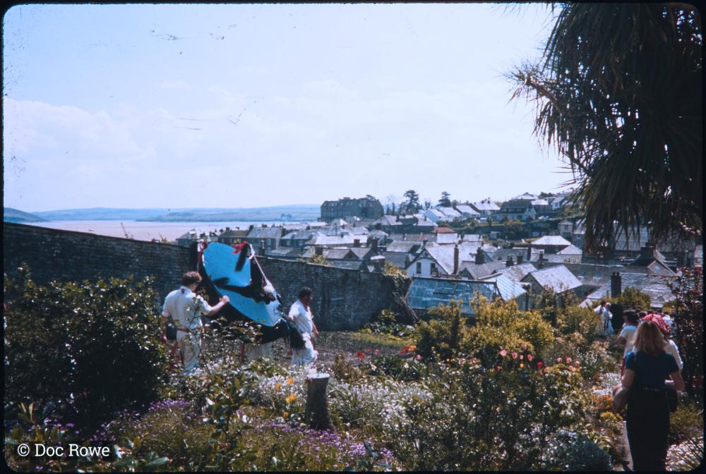 Old Oss being led through a garden, with the sea and rooftops in background
