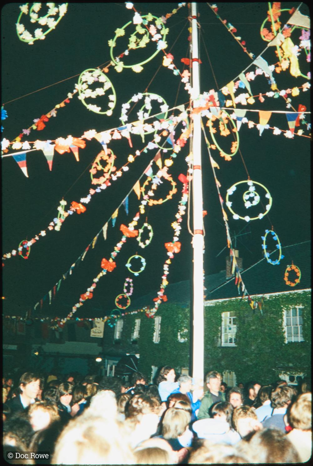 Night time, man at doorway greeted by crowd on street