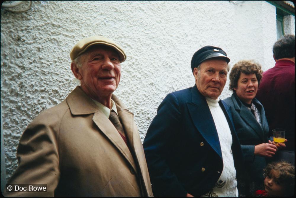 Two men and a woman stood against a wall