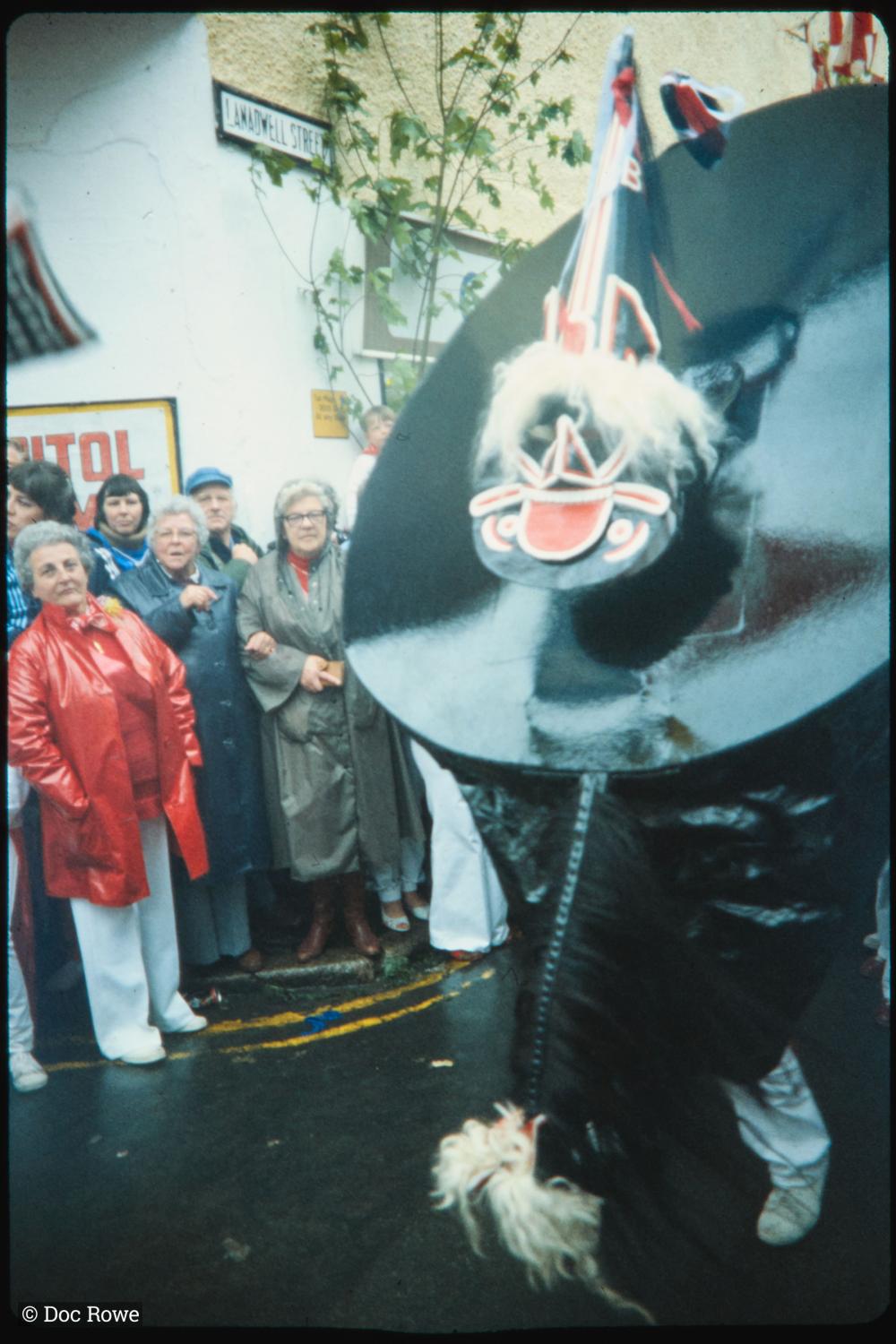 Old Oss on street corner with spectators in raincoats