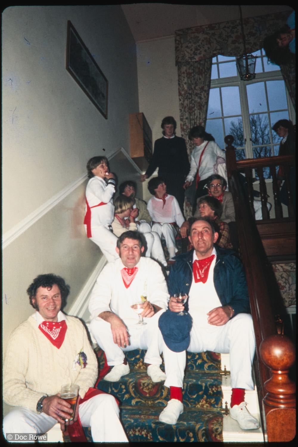 People holding drinks on steps of house