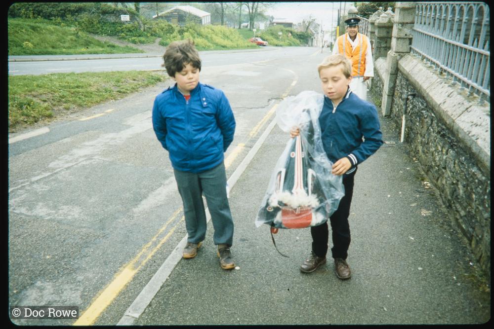 Boys on pavement with Oss hat in bag