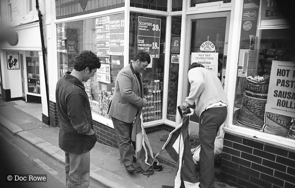 men putting up flags outside shop