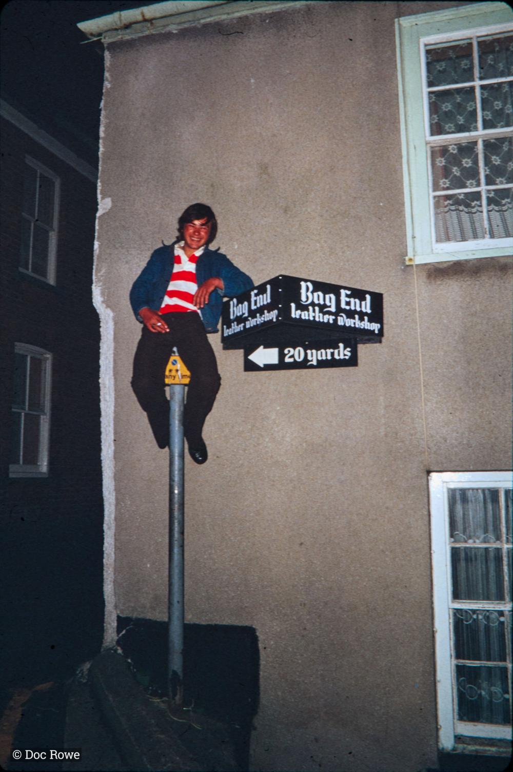 Man perched on sign at night
